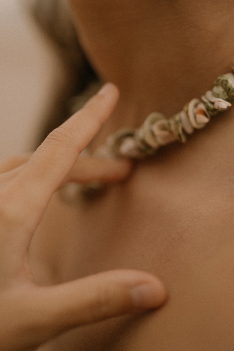 Close-up of a shell necklace on a sunlit neck