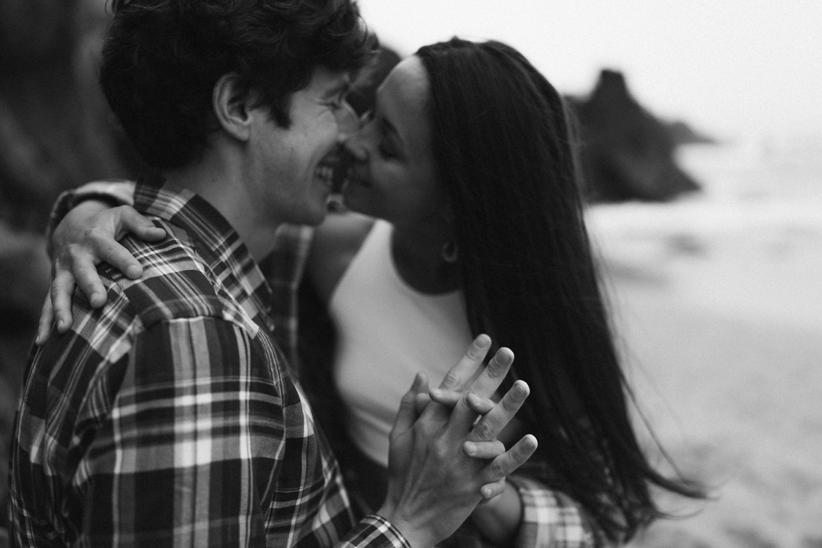 Couple holding hands on a rocky beach, black and white